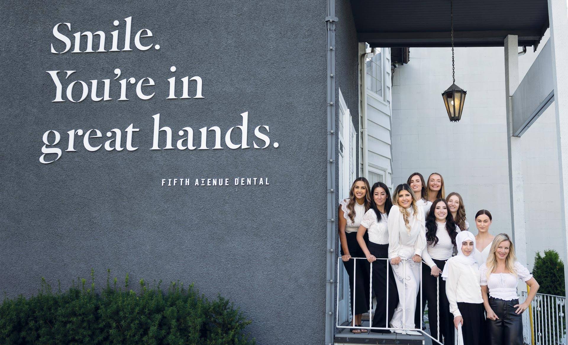 The team standing together on the stairs outside of Fifth Avenue Dental